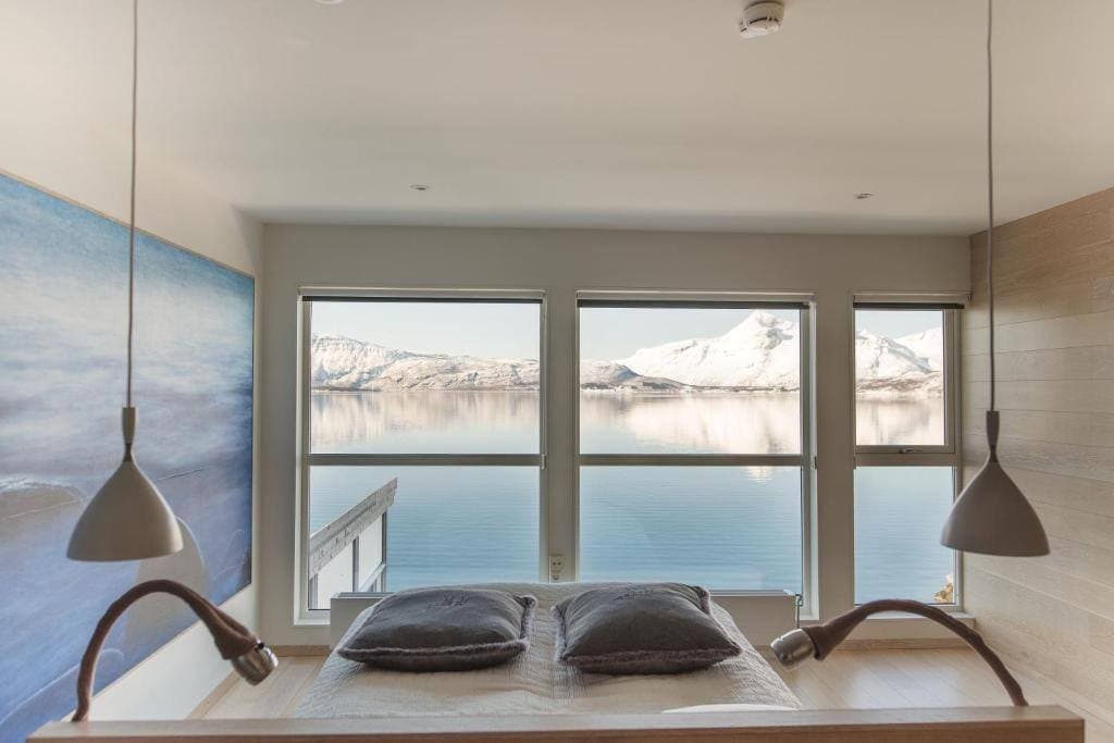 Premium dobbeltrom der sengen vender mot vinduer med utsikt over vinterfjorden og snødekte fjell