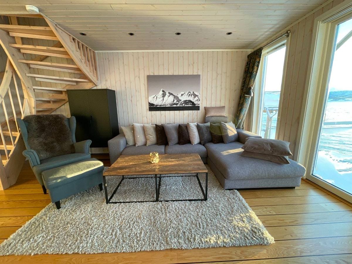 Stue med sofa, trapp og fjordutsikt