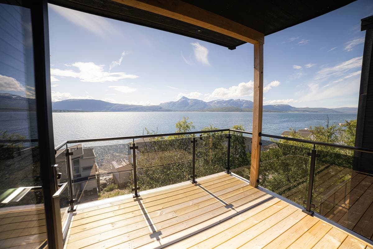 Balkong med glassrekkverk over fjorden